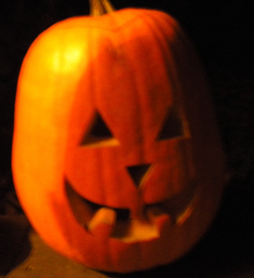 A pumpkin is  placed on the sidewalk in front of one of the houses participating in Halloween. Many carved pumpkins can be seen on Halloween night, as it is one of the many traditions of  the holiday.