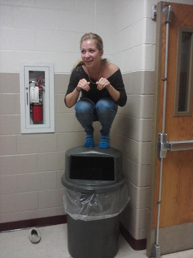 Sophomore Maddy Hoeft “owl’s” on top of a garbage can in a Milford hallway. Photo by Sarah Schroeder