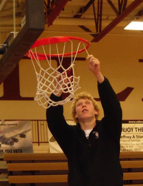 Senior Captain Chris Orr cuts down the net in the MHS Fieldhouse after his team beat Brighton, 50-31, to win the KLAA West Division Championship