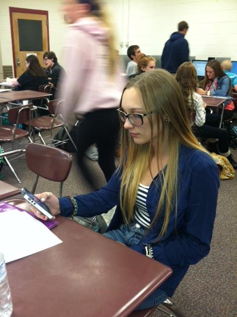 Junior Jordan Weinand uses her phone to read an article during class.  Once banned, cell phones are now allowed in many classes as the district sees the possibility of students bringing their own devices to work on class assignments. 