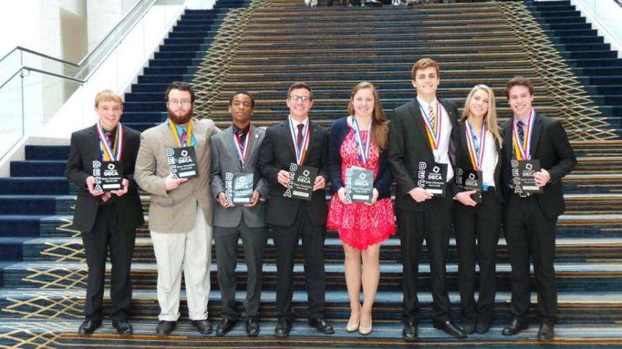 Eight students fro Milford High School hold State Champion plaques.