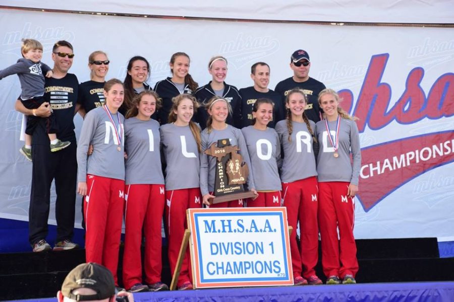 Milford girls cross country team gather on stage to accept the trophy