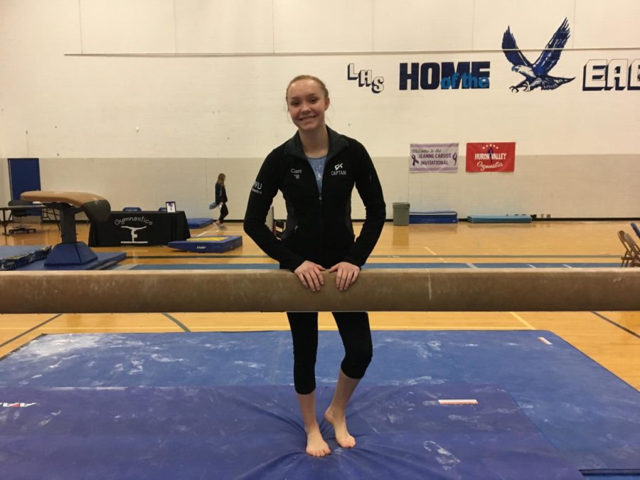 Ciara Charlick poses behind the beam at the 2018  Jeanne           Caruss Invitational, one year after her injury. (Photo by Maddie Kobylski)
