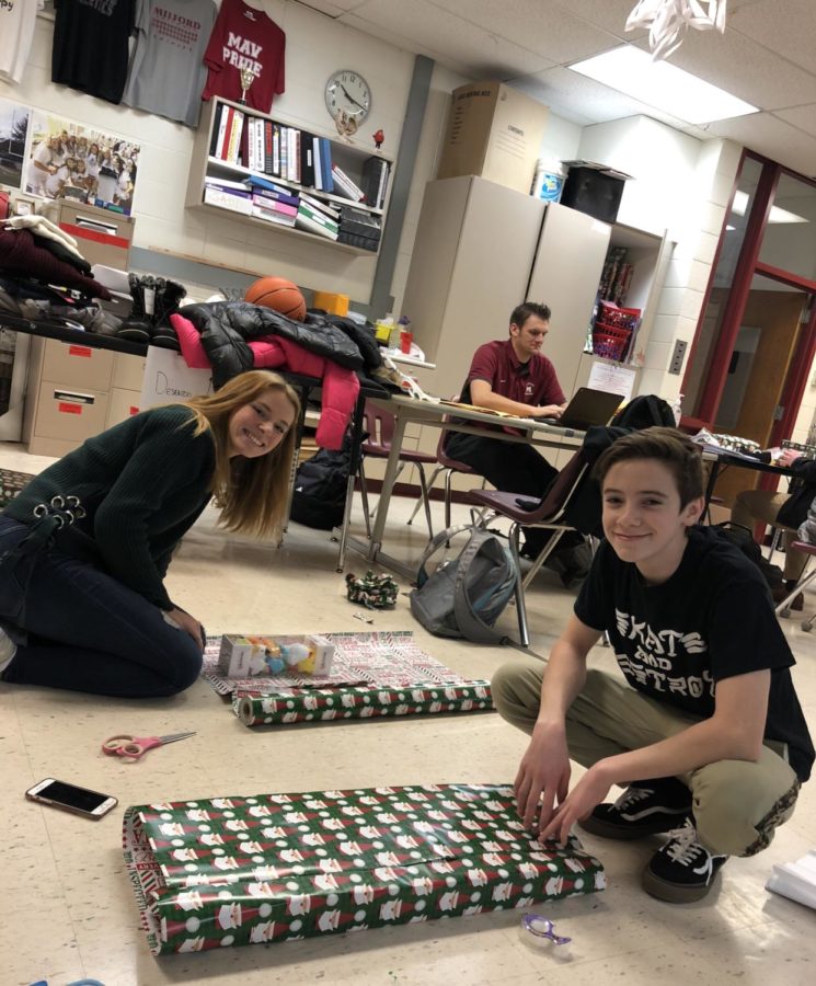 Senior Hailey Phipps (left) and sophomore Aidan Wilson (right) wrapping gifts they bought for their designated Milford Miracles family. (Photo by Abby Knapp)
