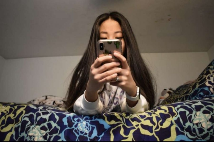 Junior Clare Miller looks at her phone in her bedroom. She said the pandemic has made her appreciate what she has. 