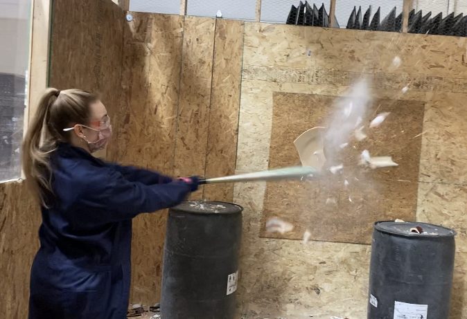 Senior Claire Adams breaks a plate in mid-air at the rage room.