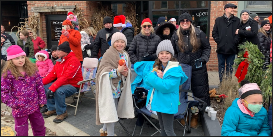 Family poses for a picture, smiles on their faces as they watch the parade go by.