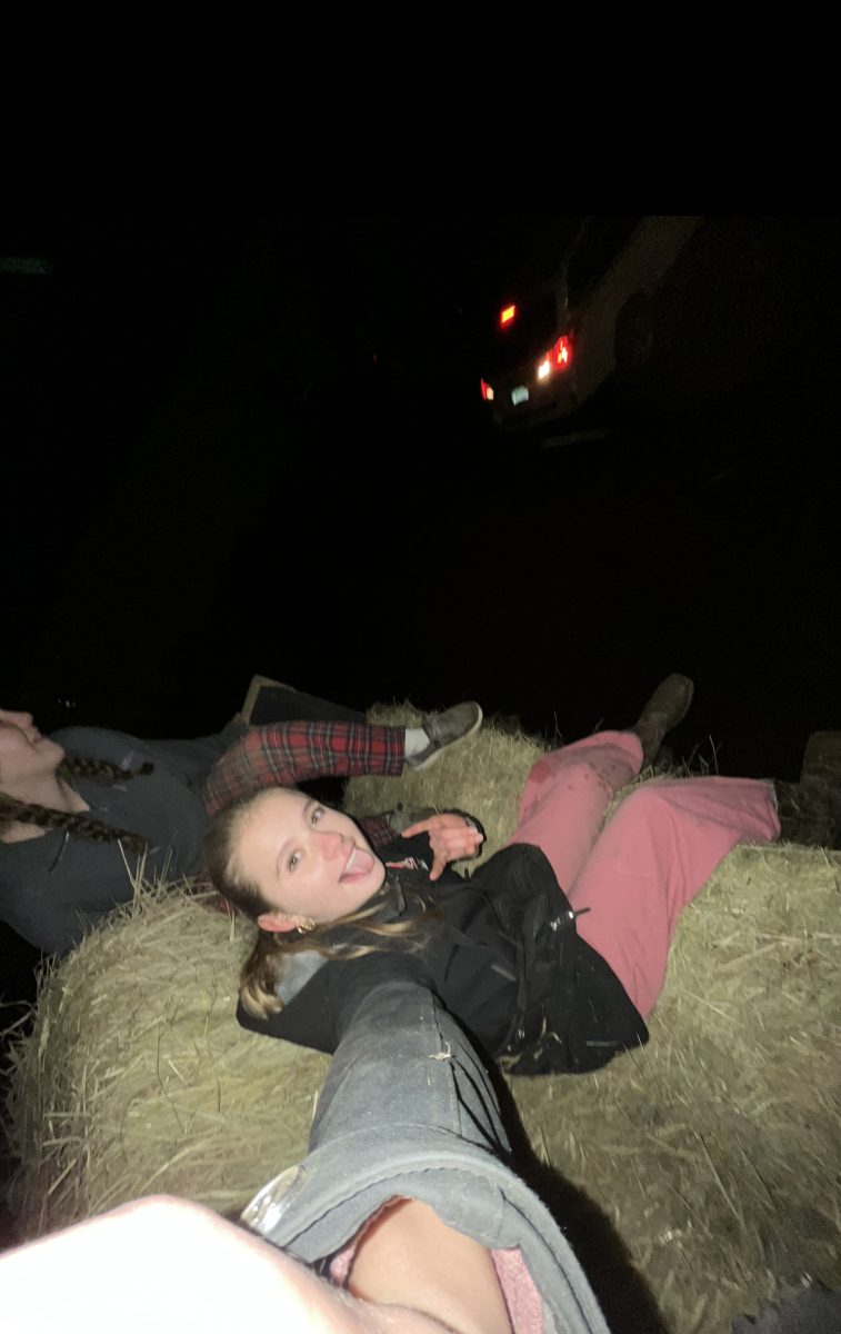 The girls taking a ride on the fork lift while moving bales of hay